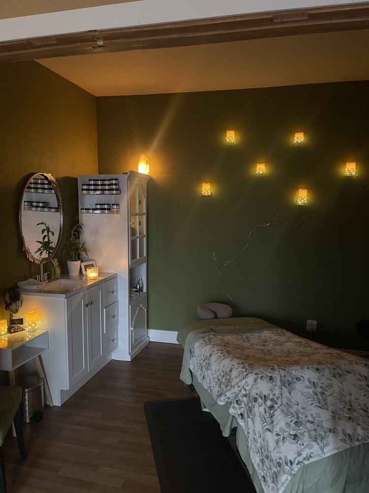 A massage room with two beds , a sink , and a mirror.