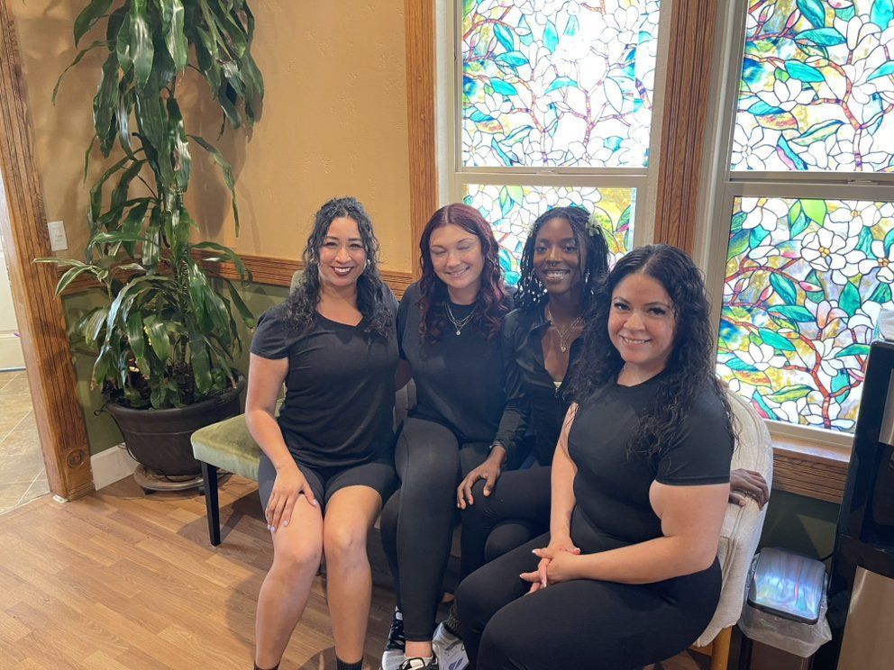 A group of women are sitting next to each other in front of a stained glass window.