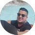 A man wearing sunglasses is sitting in a swimming pool.