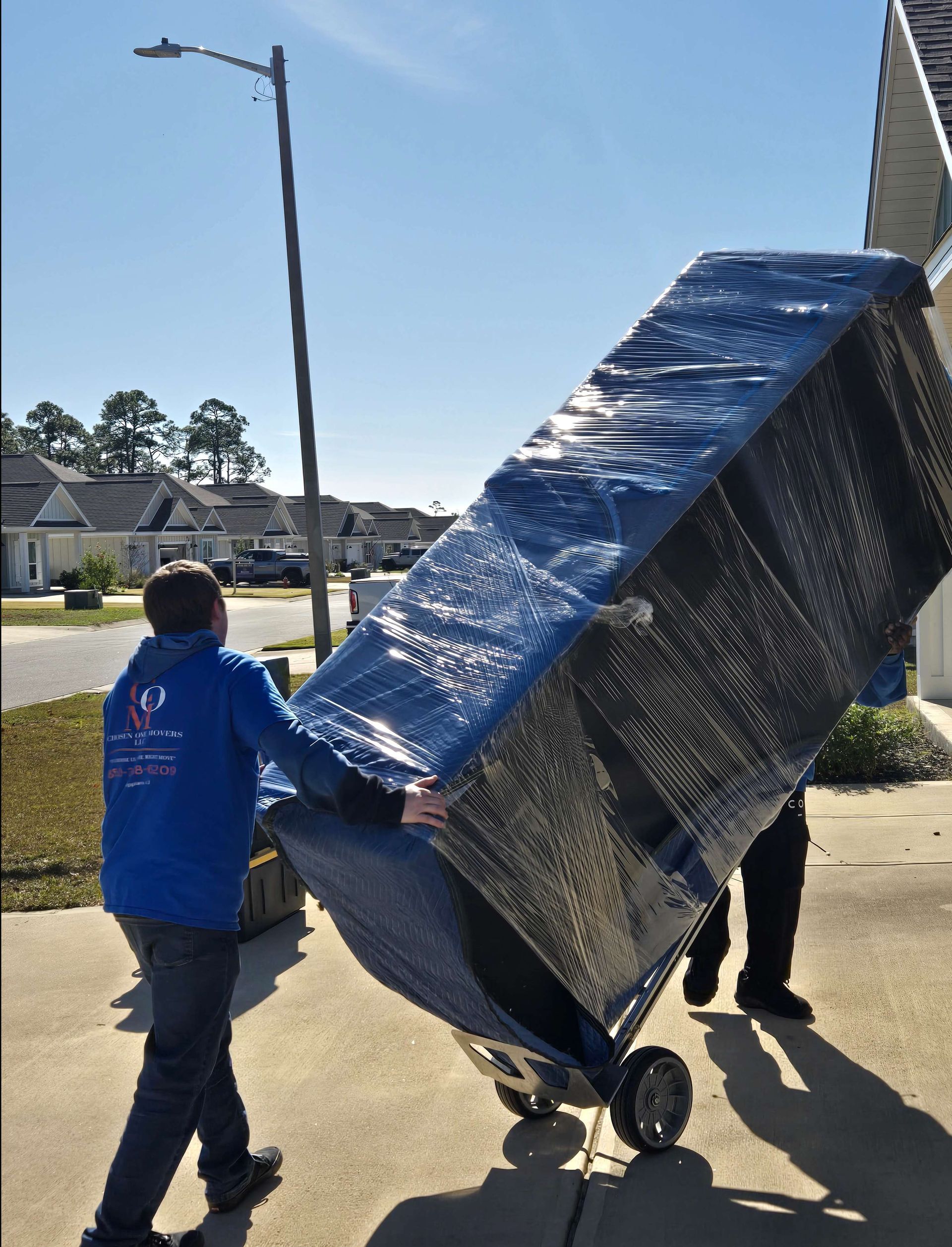 Two men are carrying a large piece of furniture on a dolly