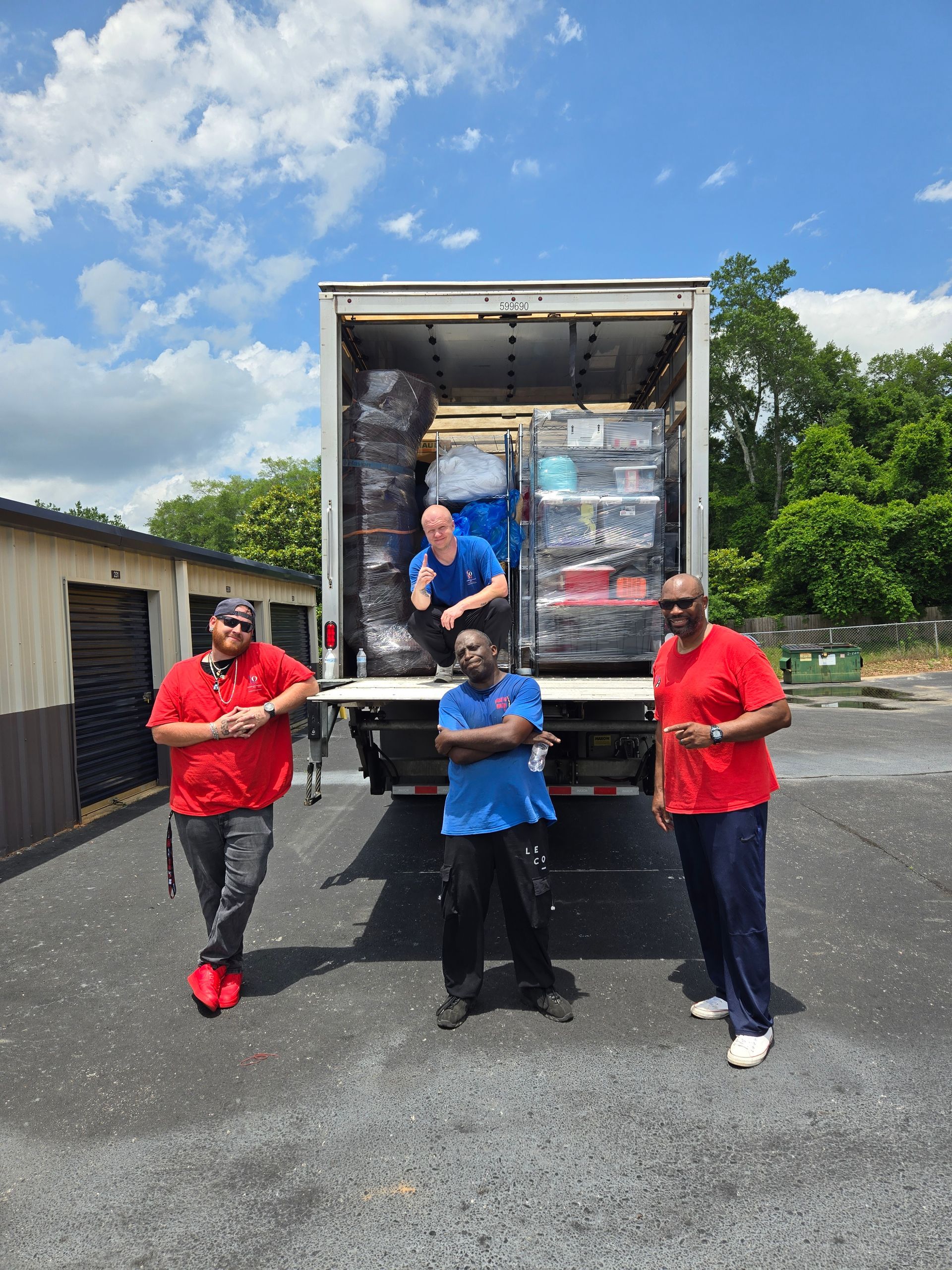 Three men are standing in front of a truck full of boxes