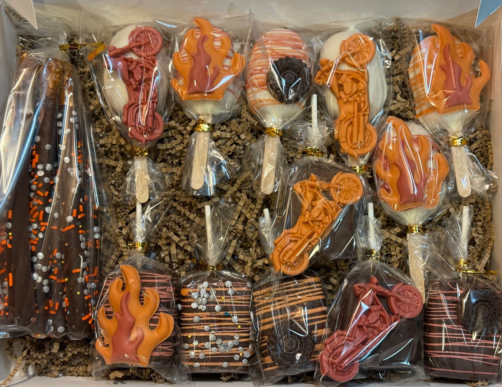 A box filled with a variety of chocolate covered treats and lollipops.