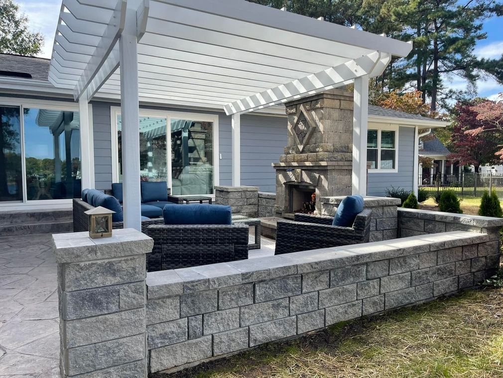 A patio with a pergola and a fireplace in front of a house.