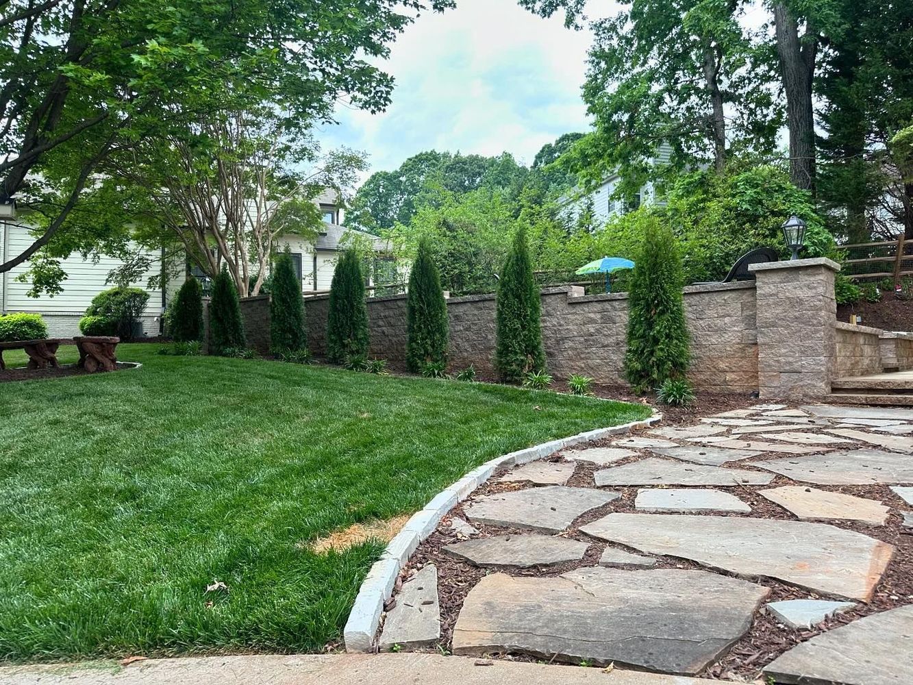 There is a stone walkway leading to a picnic table in the backyard.