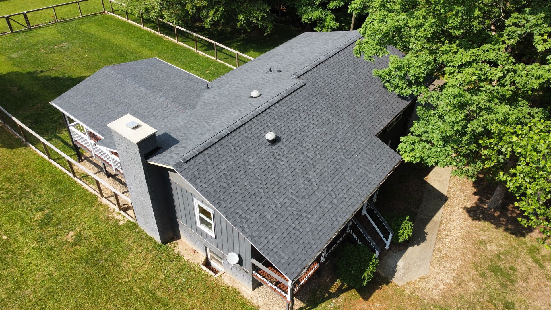 An aerial view of a house with a fence and trees in the background.