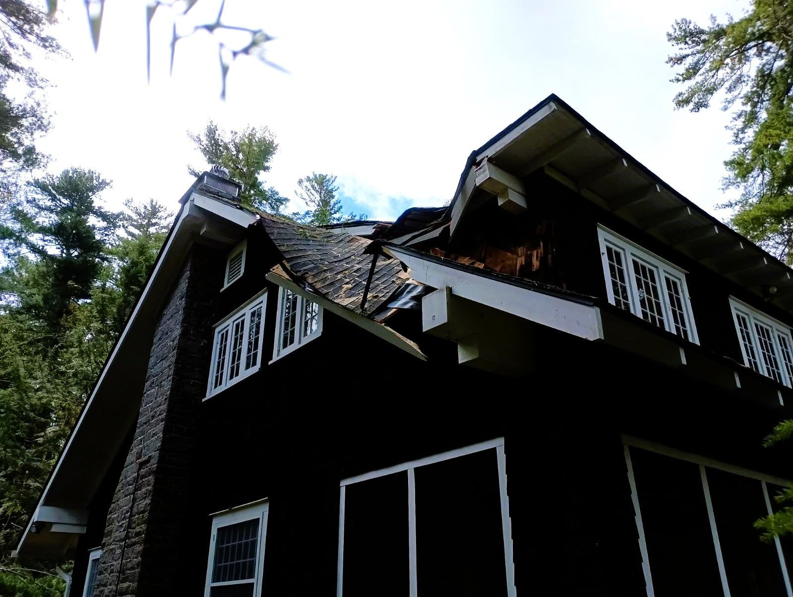 A black house with a roof that has been damaged