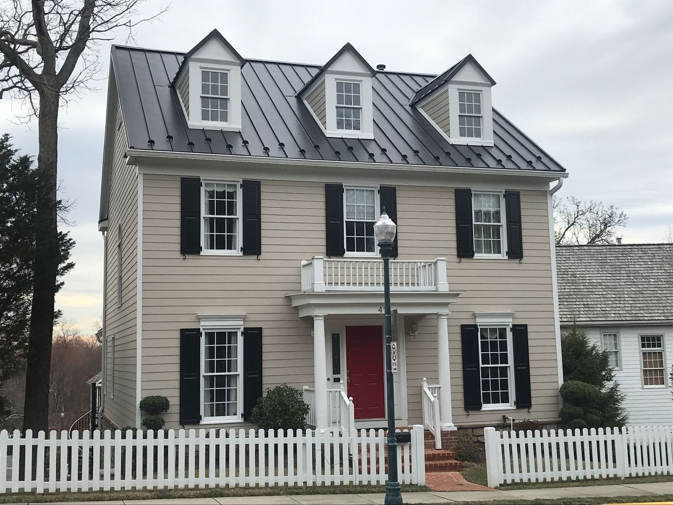 A large house with black shutters and a white picket fence