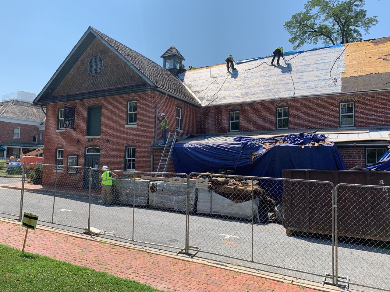 A large brick building is being remodeled with a roof being installed.