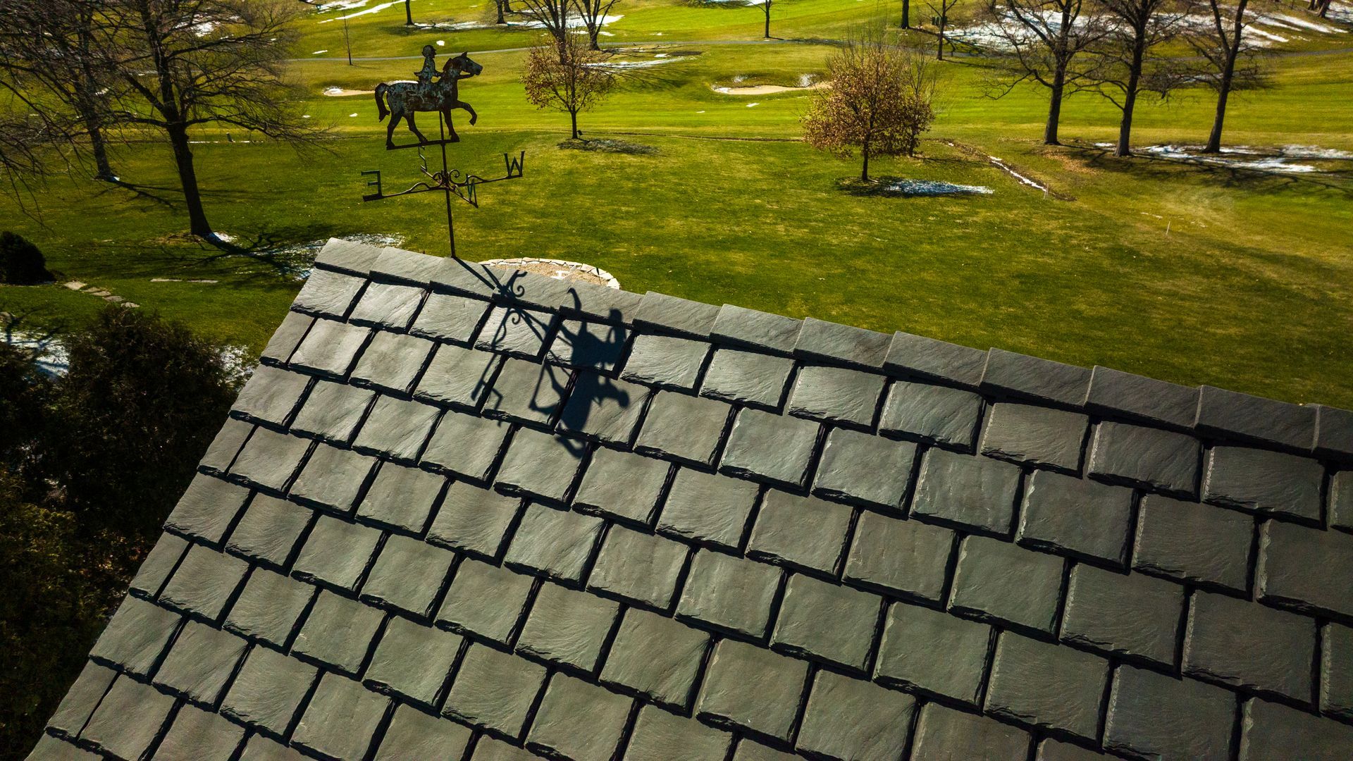 An aerial view of a roof with a weather vane in the background