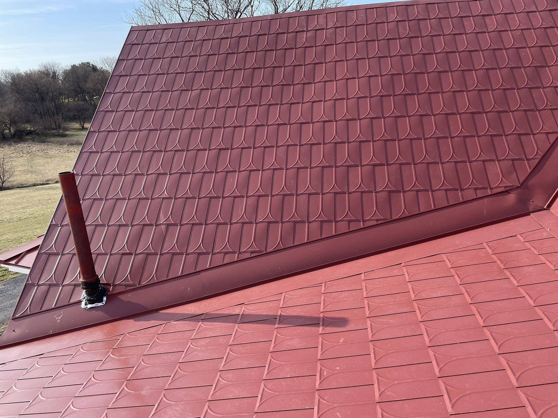 Red metal roof with chimney and angled edges.