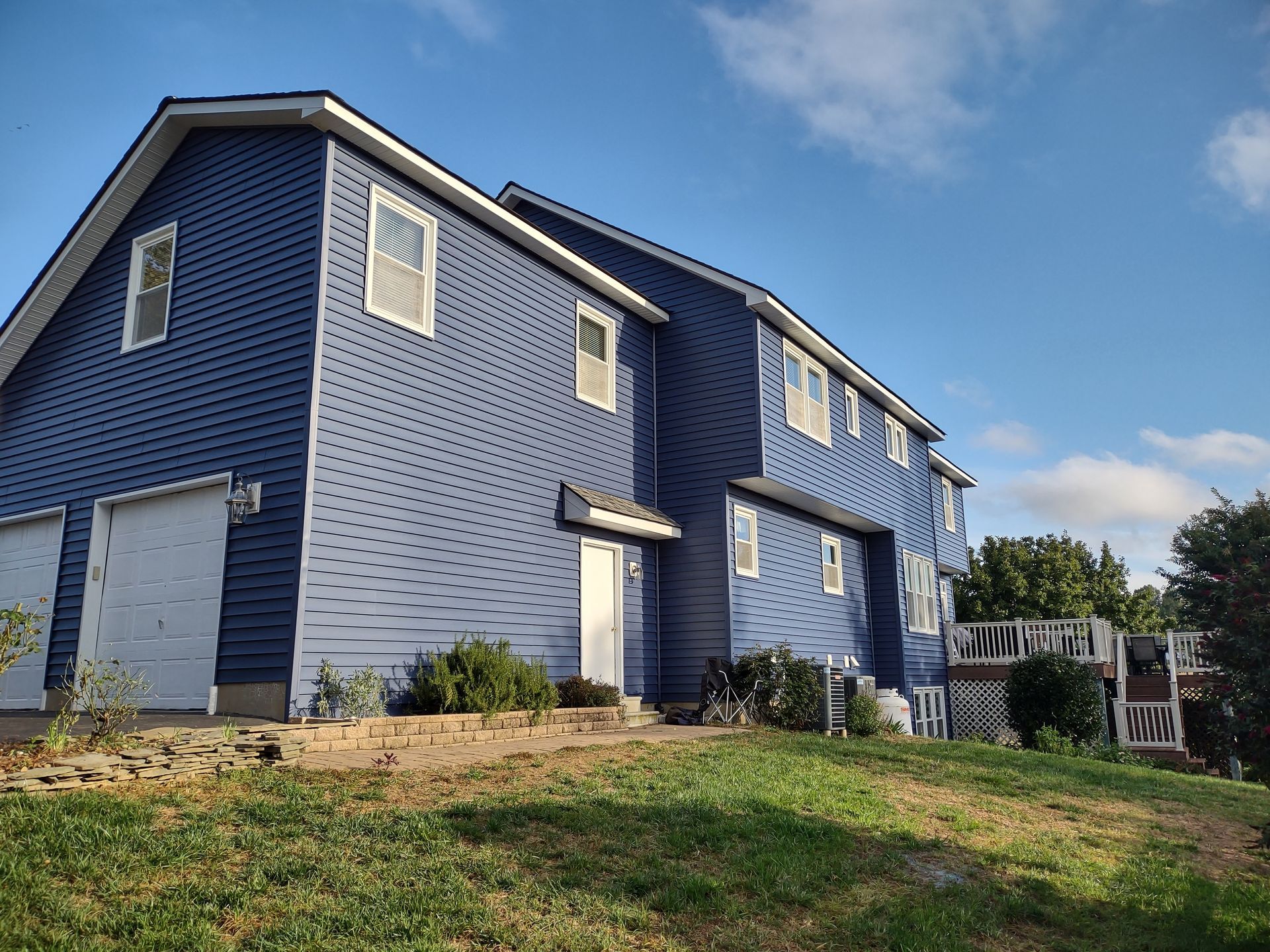 Blue-sided multi-story building with garage doors and white trim under a blue sky.