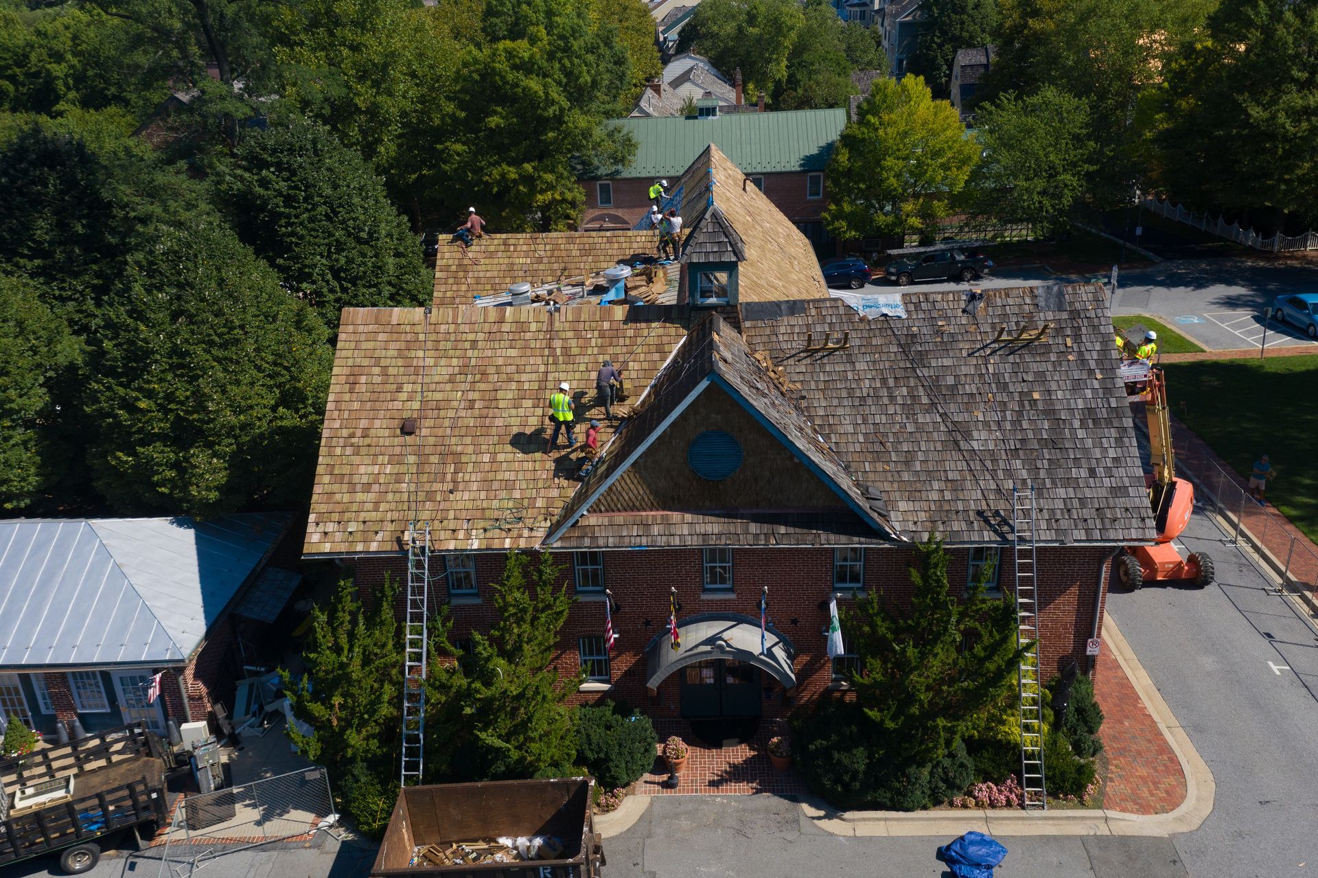 An aerial view of a brick building with a wooden roof being installed.