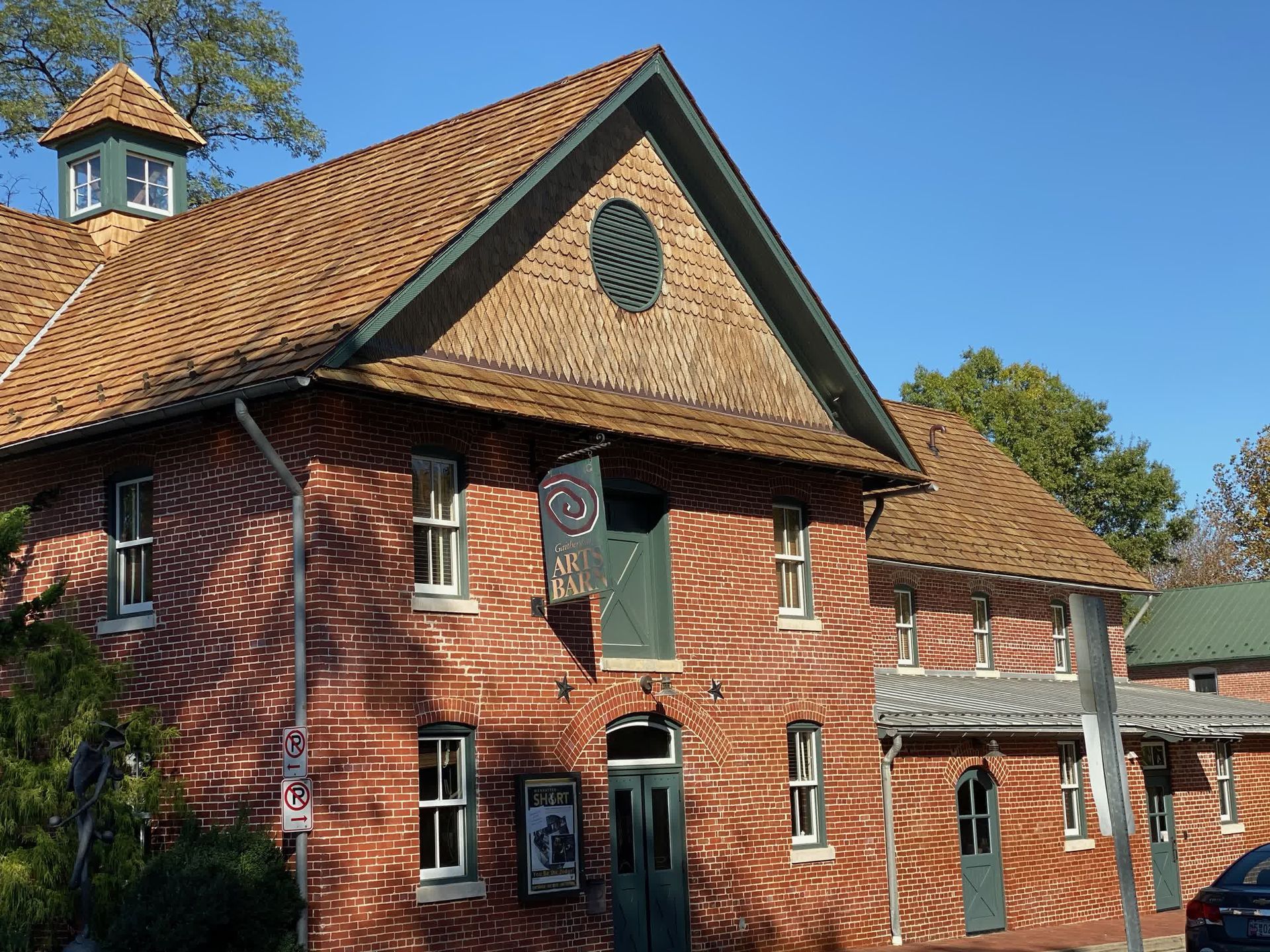 Brick building with a brown tile roof, green trim, and a circular window.
