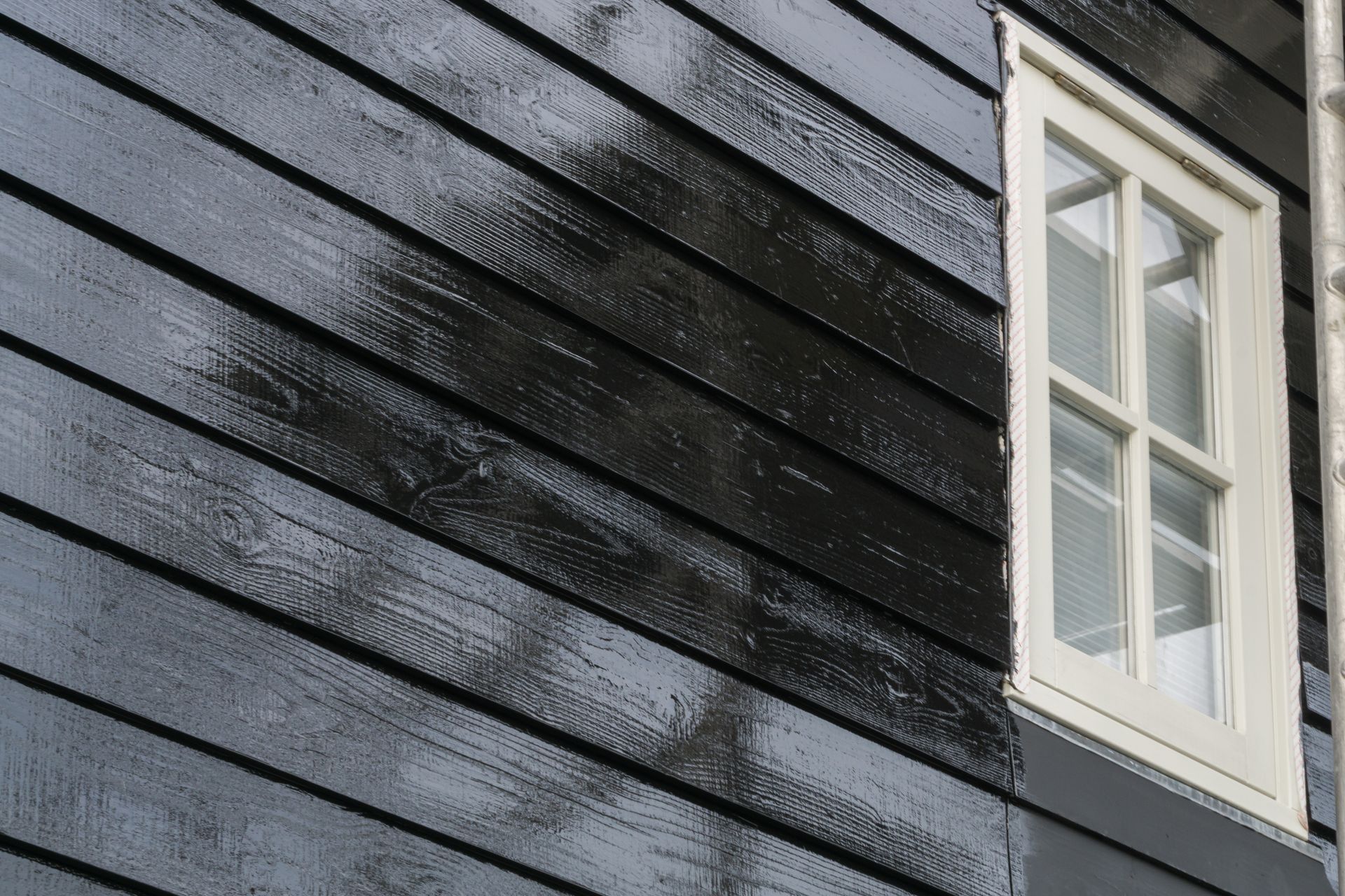 Dark blue painted wooden siding with a white window frame.