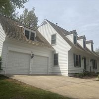 White house with three-car garage and brown shingle roof on a sunny day.