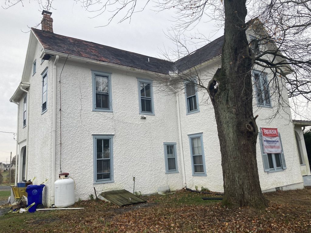 White house with blue window frames, a tree in front, and a 