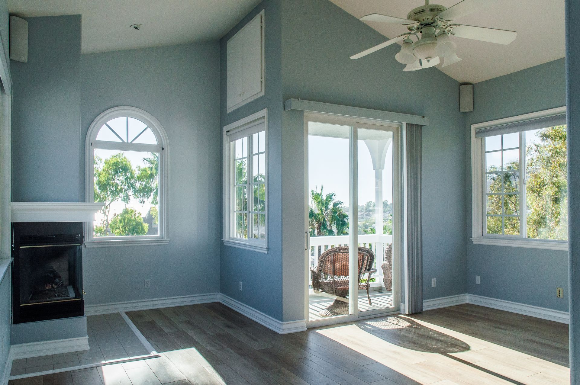 Empty room with blue walls, fireplace, large windows, and a sliding door to a balcony.