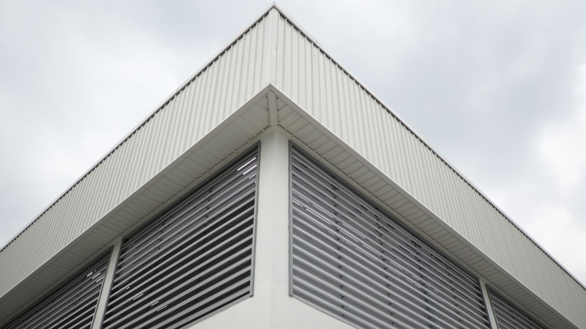 Looking up at the corner of a building with blinds on the windows.