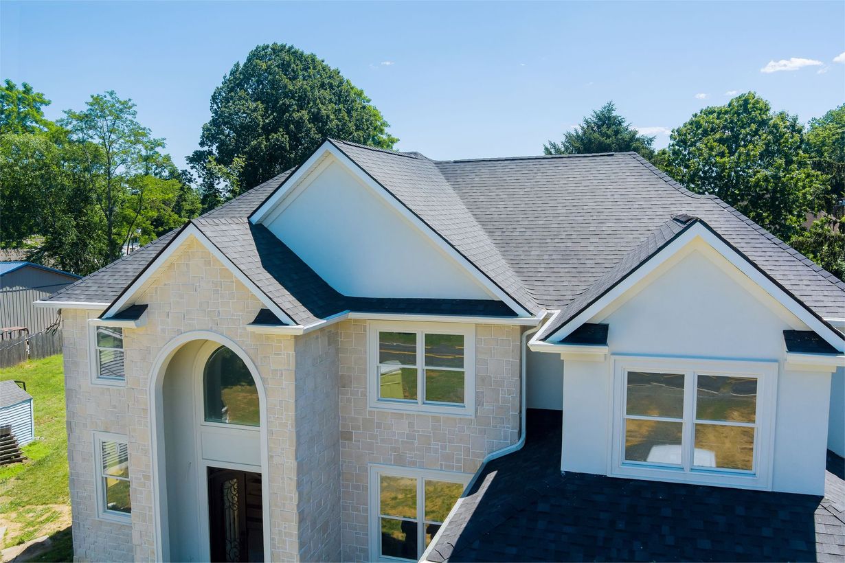 An aerial view of a white house with a black roof