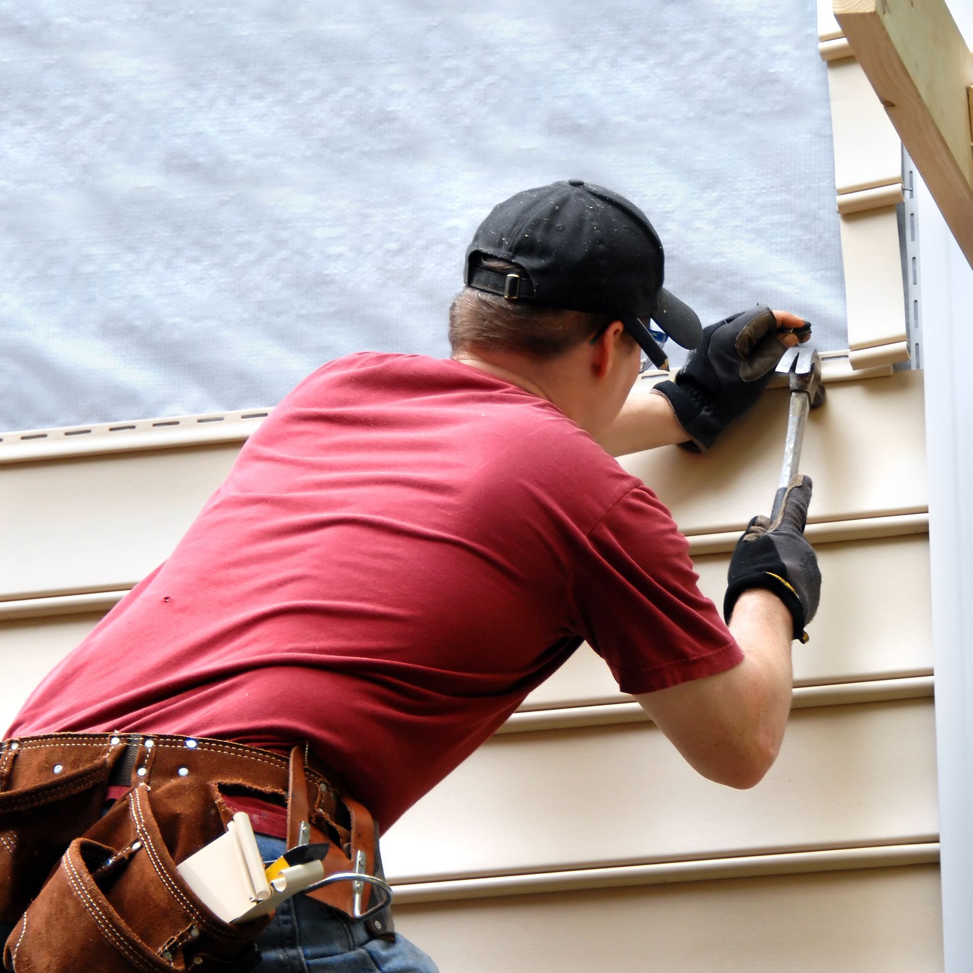 A man in a red shirt is working on a wall