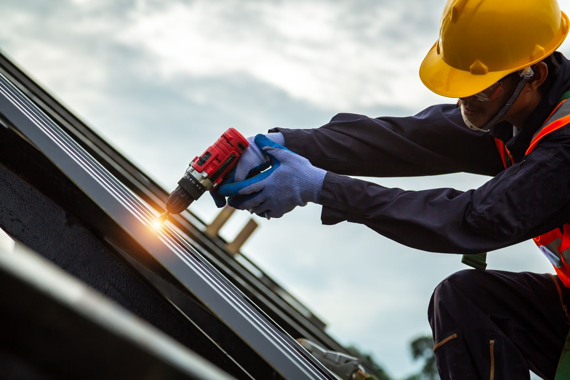 A man is working on a roof with a drill.