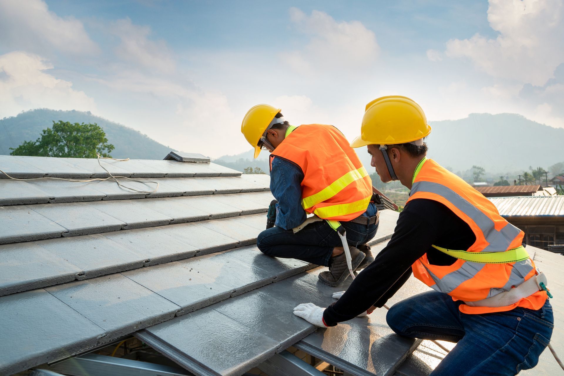 Two construction workers are working on a roof.