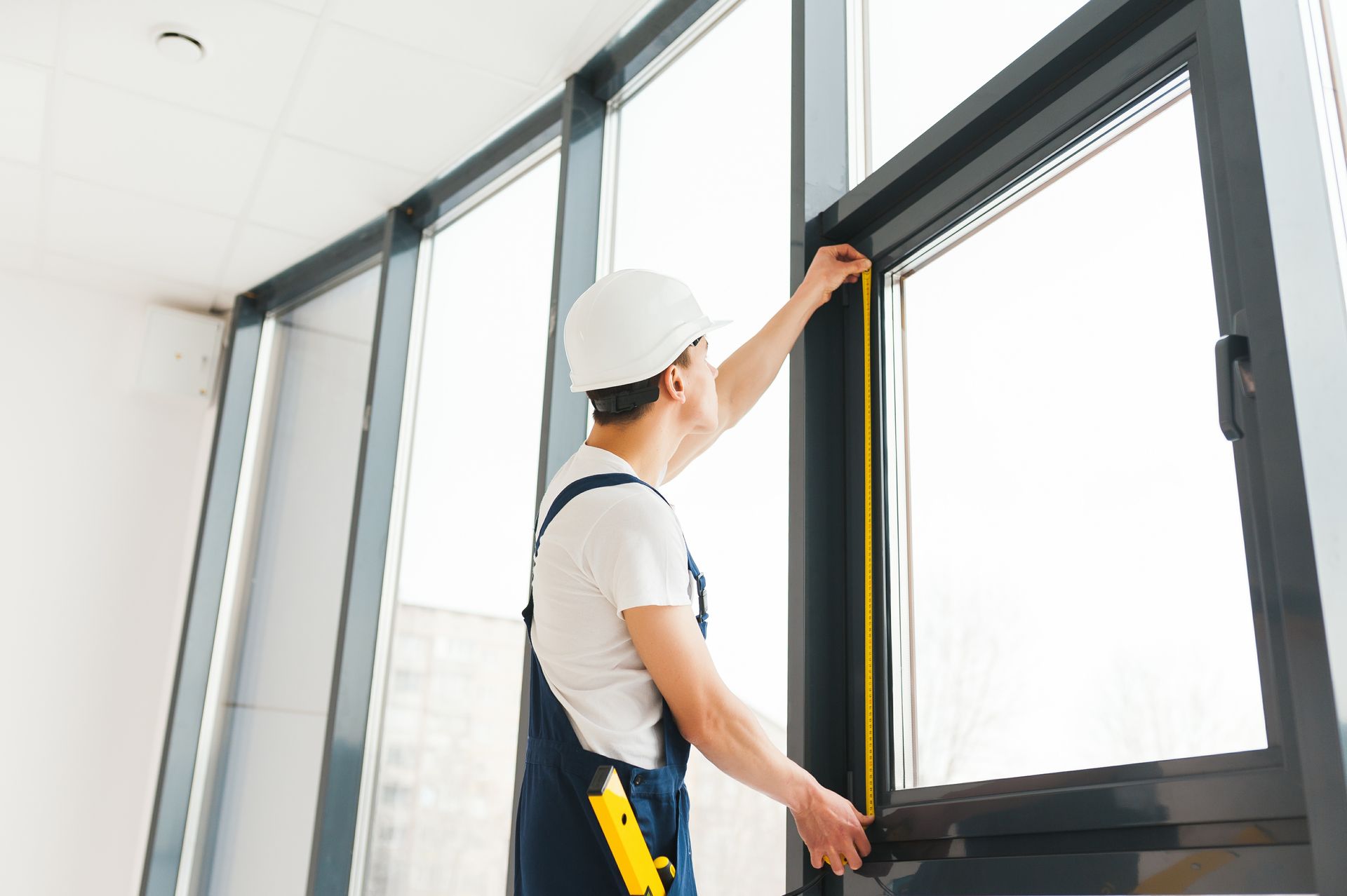 A man is measuring a window with a tape measure.