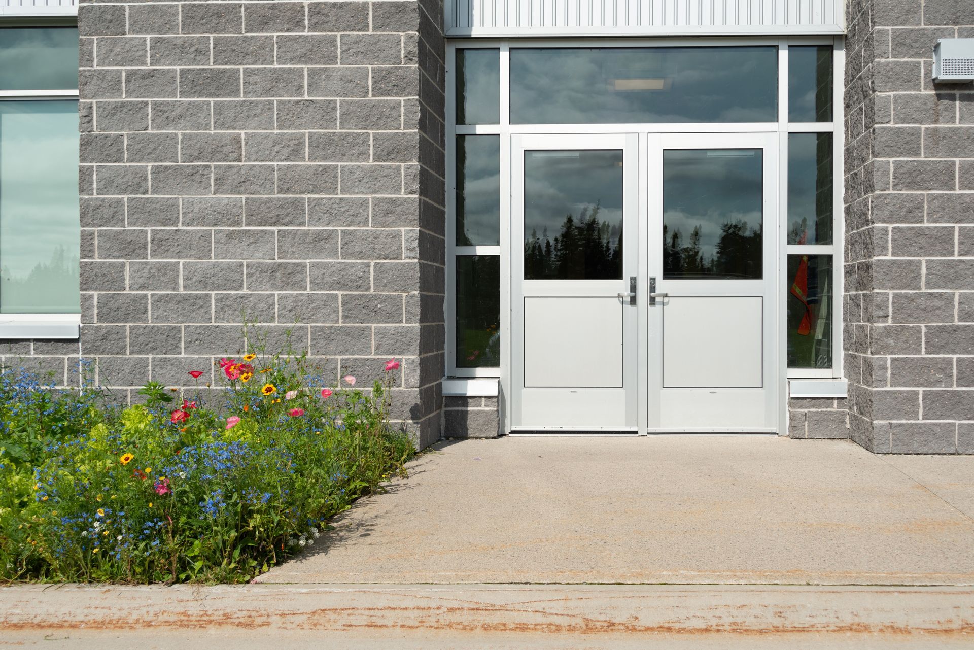 A brick building with a white door and flowers in front of it