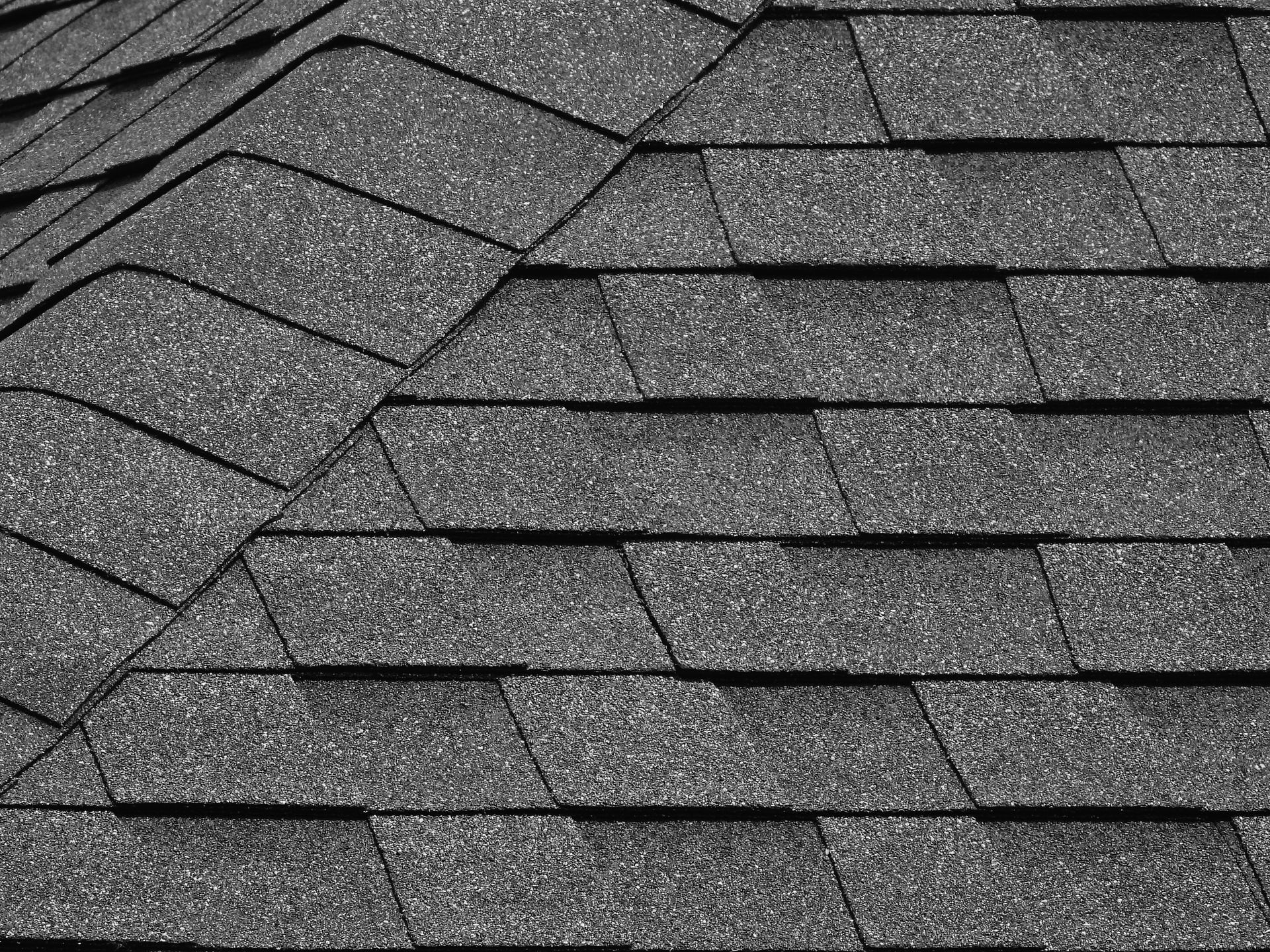 A brick house with a black roof and a chimney.