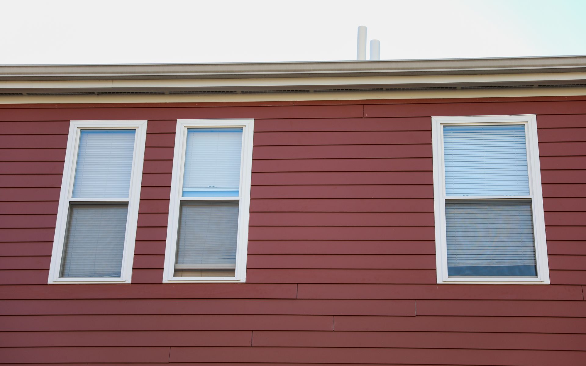 A red building with three windows and a blue sky in the background.