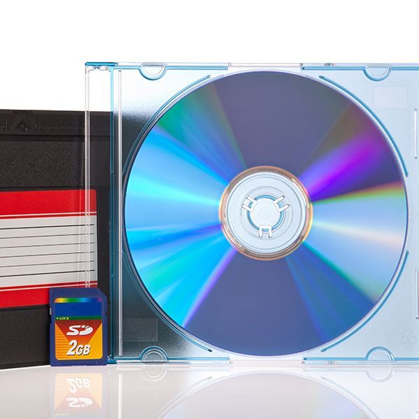 CD case with a reflective CD beside stacked floppy disks and a memory card