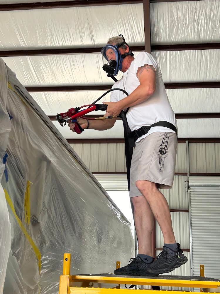 A man wearing a gas mask is standing on a scaffolding holding a tool.