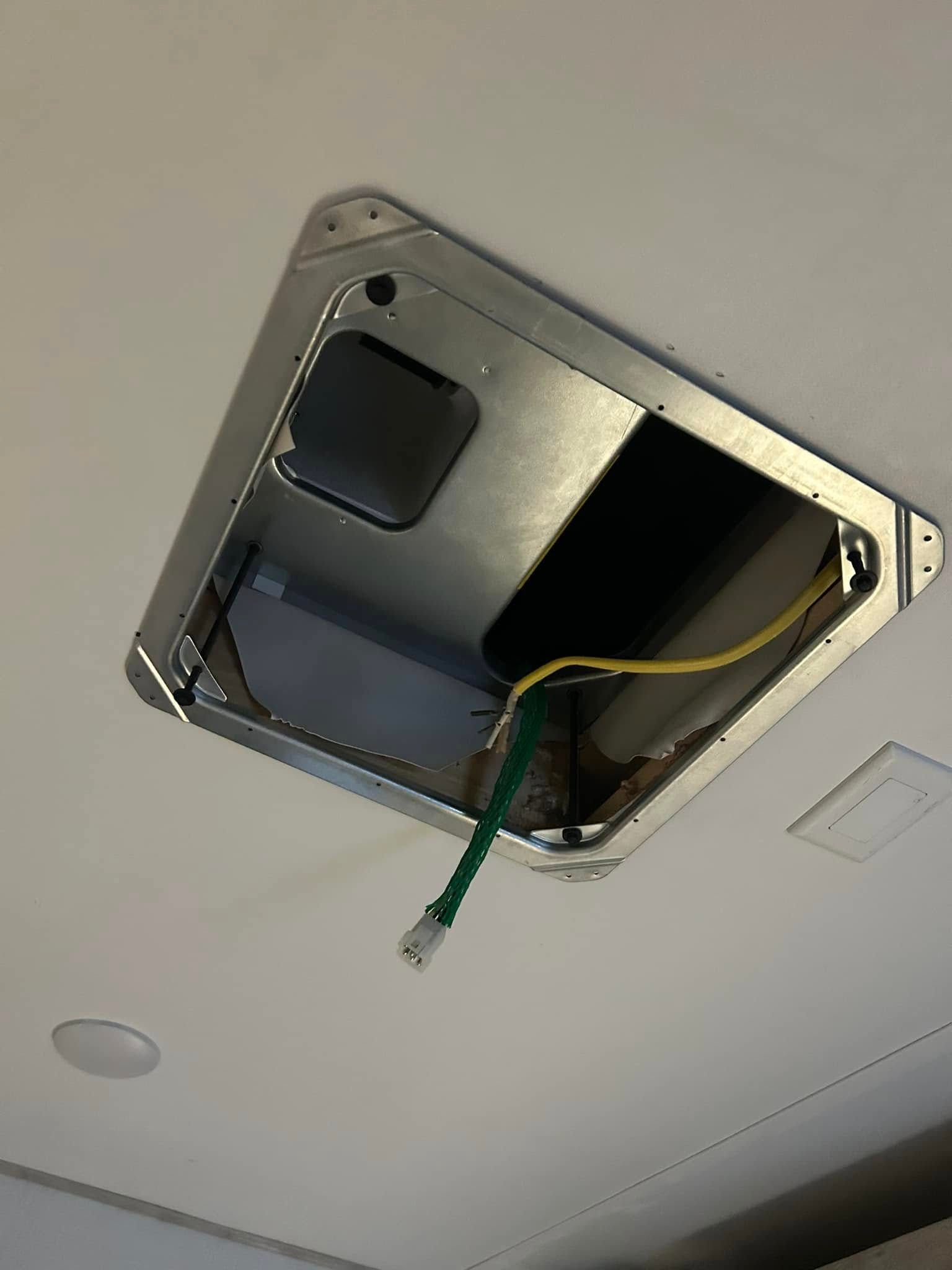 A hole in the ceiling with a green hose coming out of it.