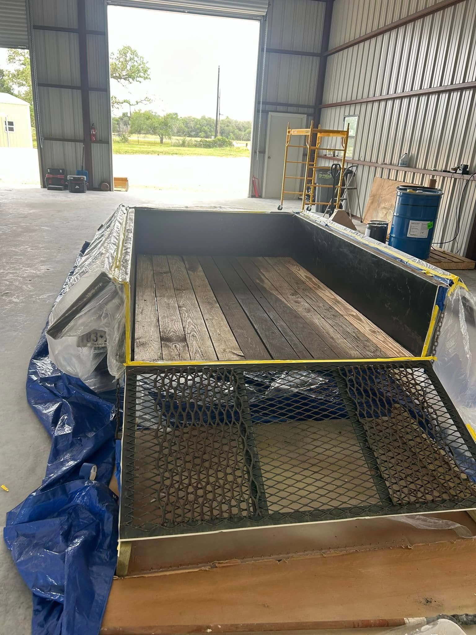 A trailer is sitting in a garage with a blue tarp covering it.