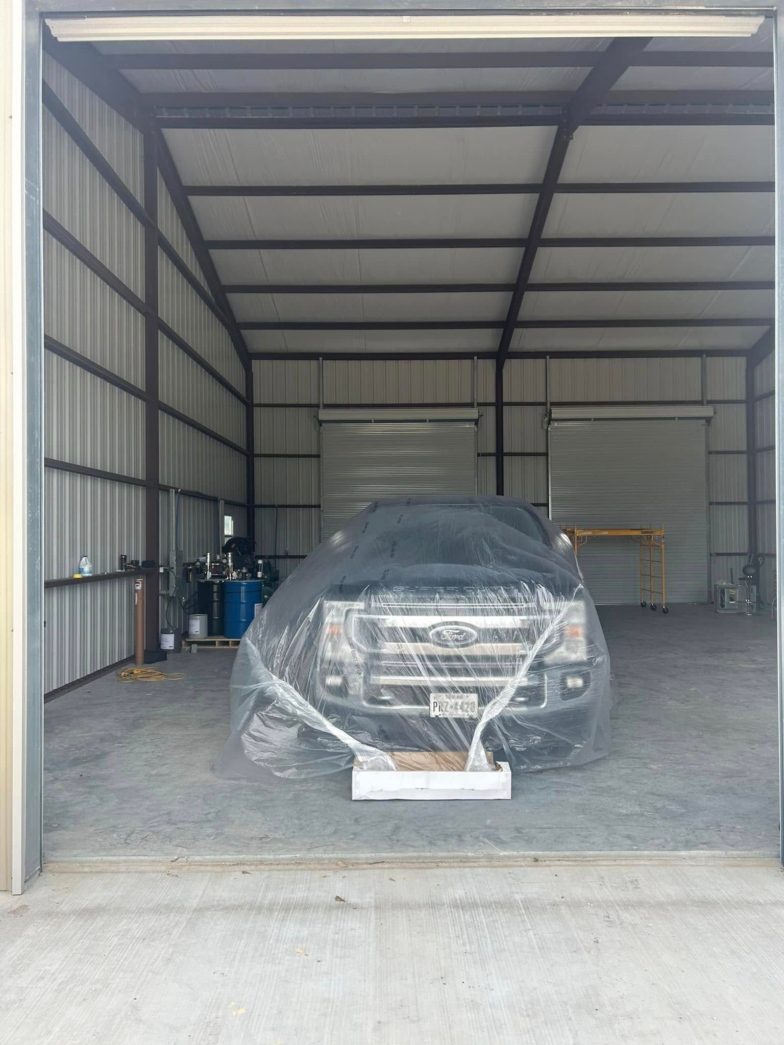 A truck is covered in plastic in a garage.