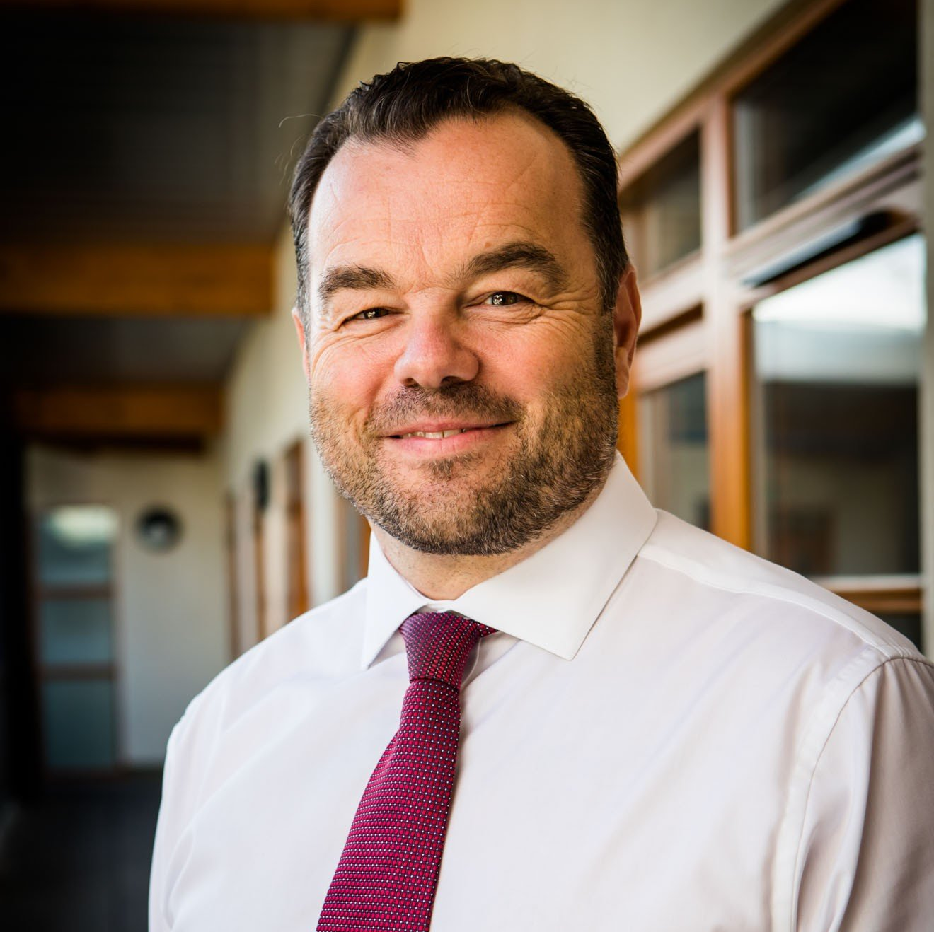 A man with a beard wearing a white shirt and purple tie