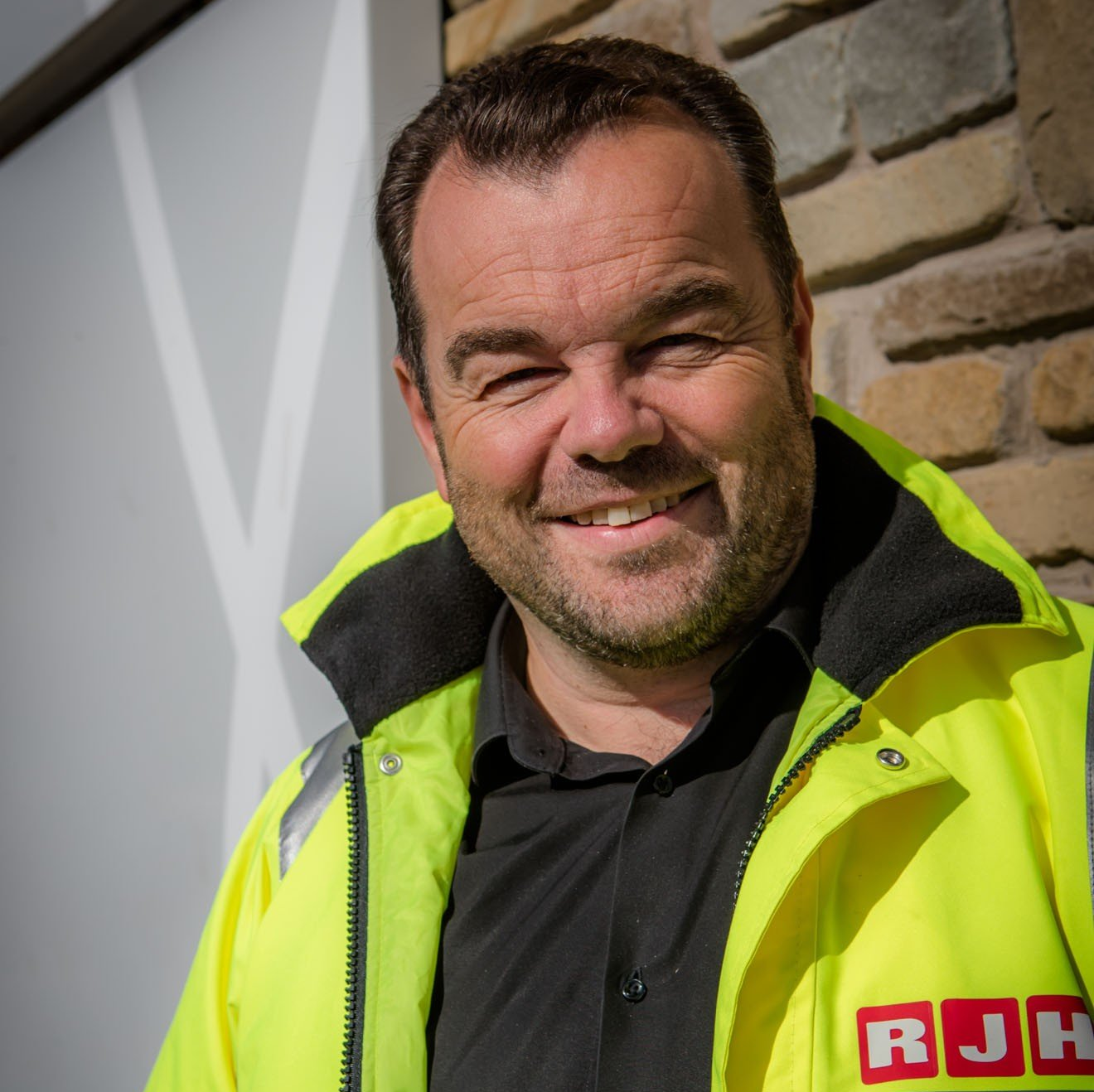 A man wearing a yellow jacket that says rjh on it