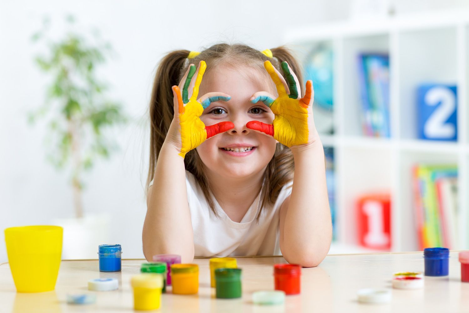 cheerful kid girl showing her hands painted in bright colors