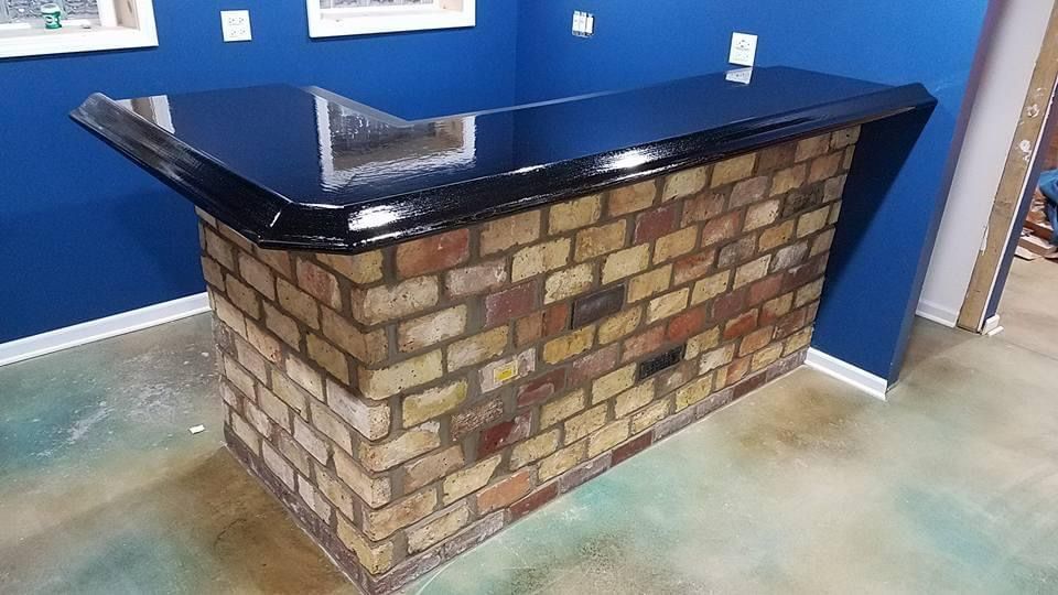 A brick bar with a black counter top in a room with blue walls.