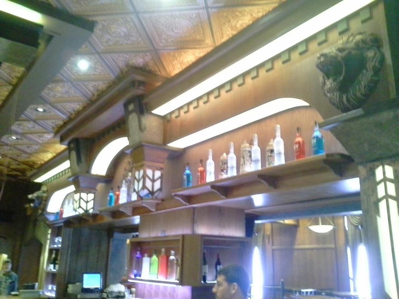 A man sits at a bar with bottles on shelves