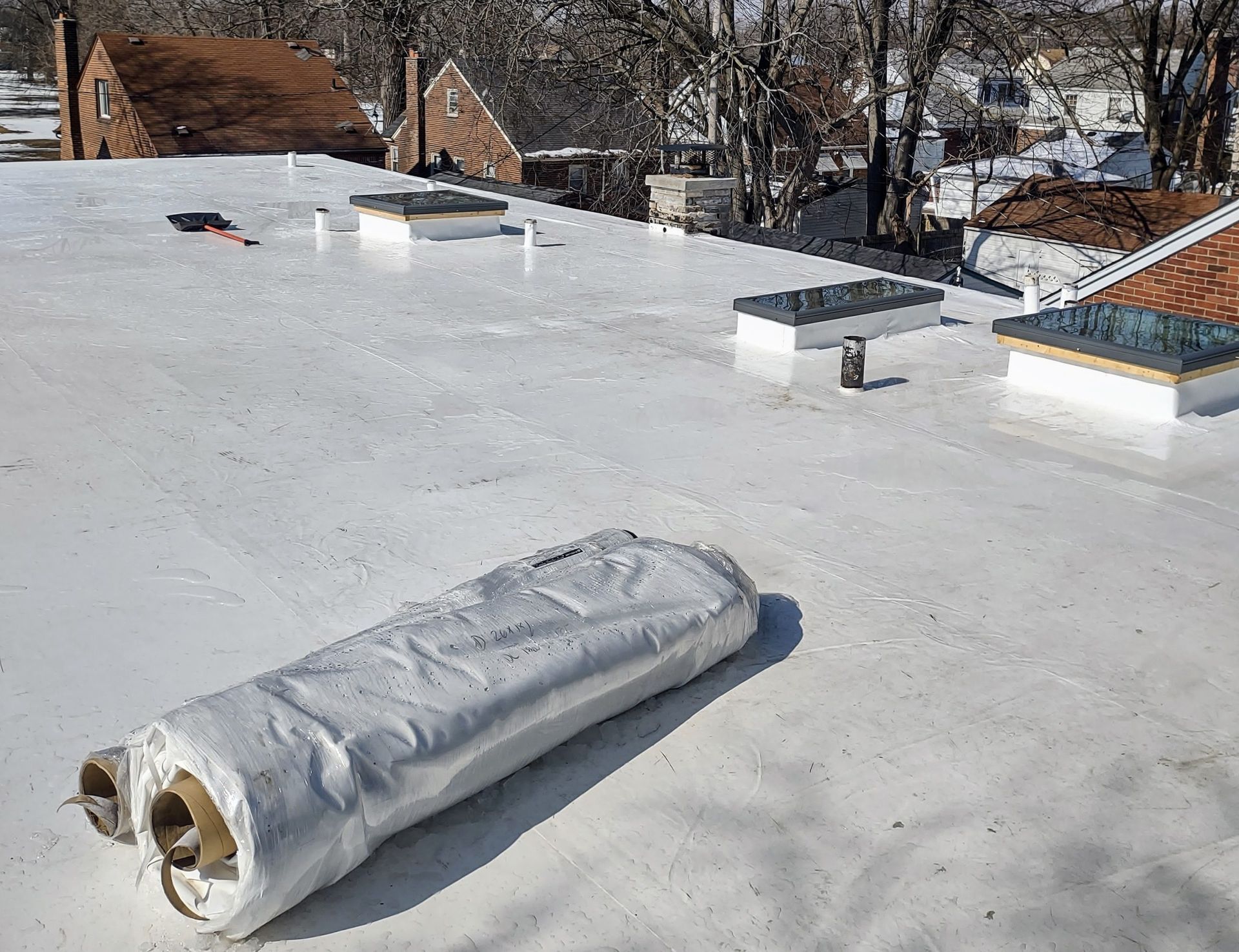 A roll of aluminum foil is sitting on top of a white roof.