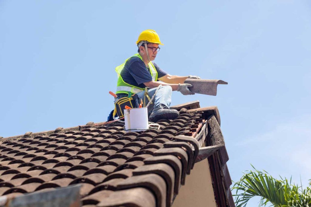 A man is sitting on top of a tiled roof.