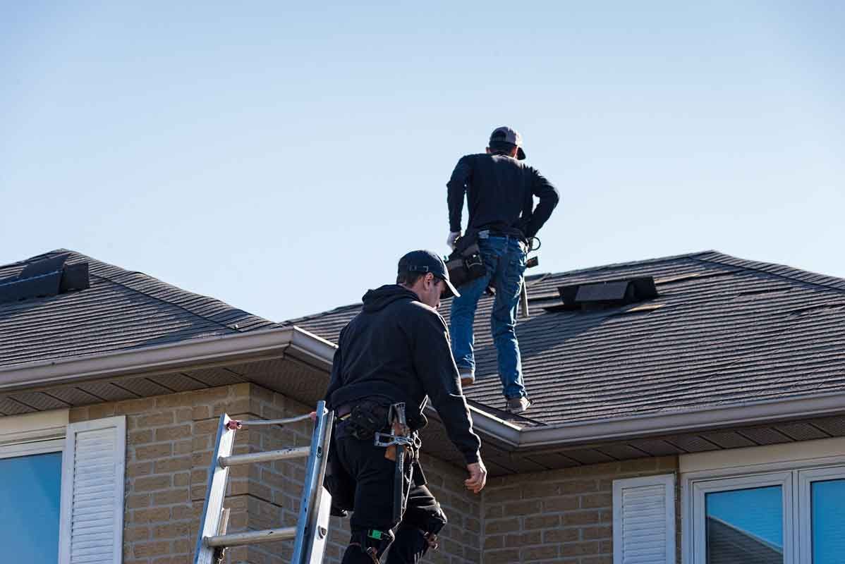 Two men are working on the roof of a house.