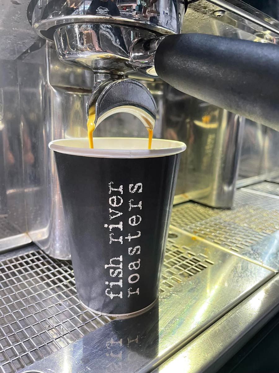 A Cup of Coffee is Being Poured Into a Fish River Roasters Cup — Cafe Nosh in Taree, NSW