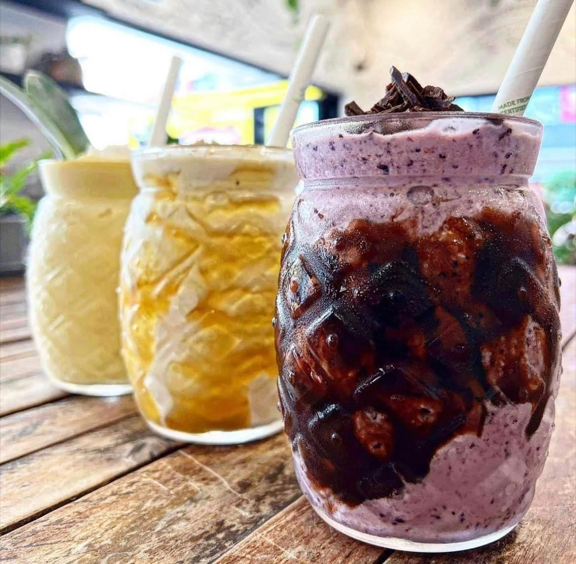 Three Jars of Milkshakes With Straws on a Wooden Table — Cafe Nosh in Taree, NSW