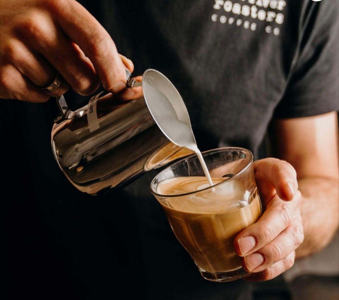 A Barista Pouring Milk Into A Coffee Cup — Cafe Nosh in Taree, NSW