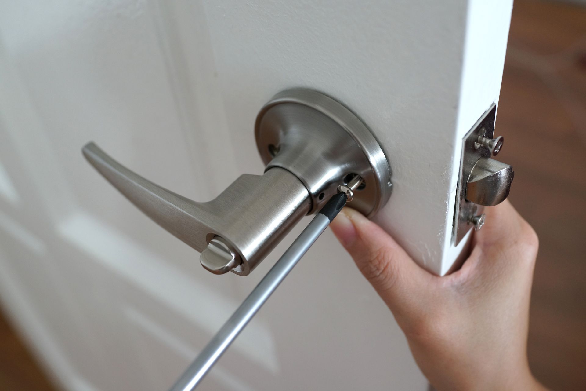 Hand using screwdriver to tighten screw on door handle