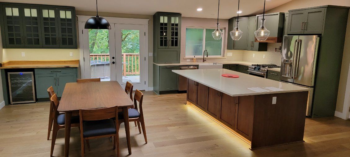 Kitchen with green cabinets, a large island with under-glow lights, and a wooden dining table.