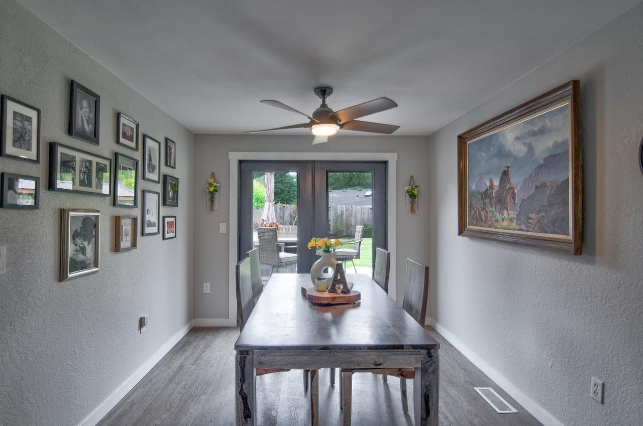 Dining room with long wooden table, framed artwork, and French doors leading outside.
