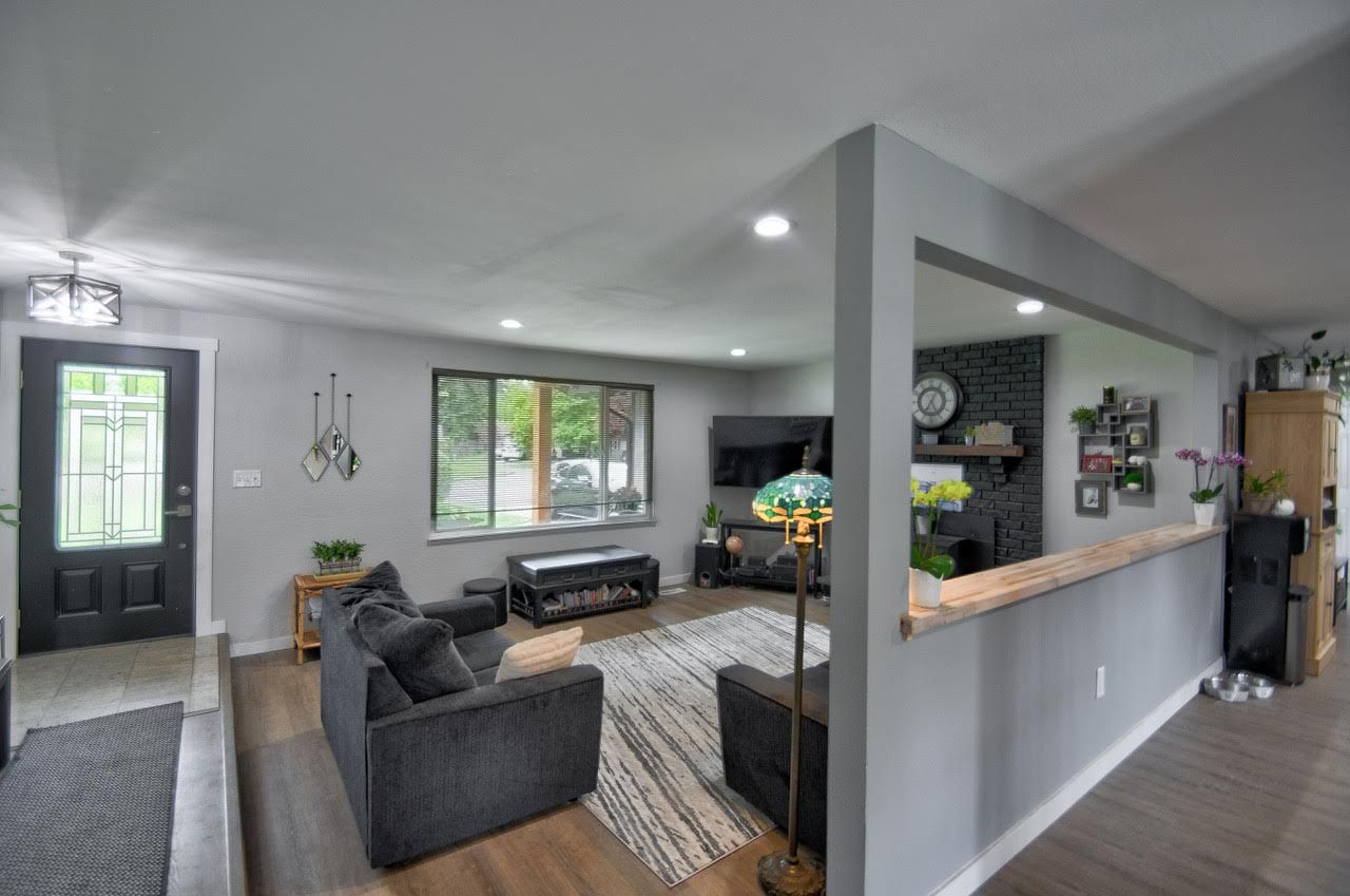 Gray living room with dark gray furniture, a fireplace, and a large window.